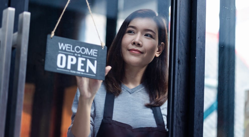 Small business owner turning over the open sign to her shop